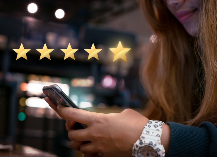 Millennial woman submitting star rating feedback on mobile device after internet shopping experience