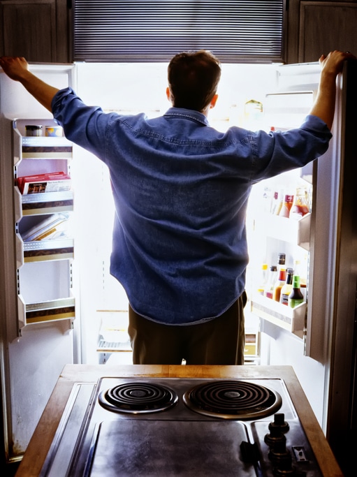 Man looking into refrigerator for food.