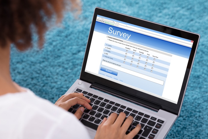 Close-up Of A Woman's Hand Filling Survey Form On Laptop